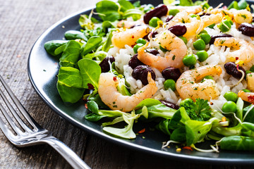 Prawns with rice and vegetables on wooden table