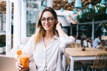 Smiling woman at restaurant holding glass of juice