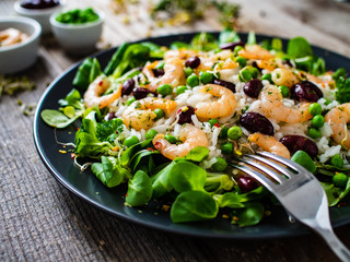 Prawns with rice and vegetables on wooden table