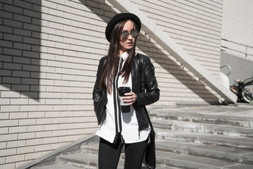 beautiful girl posing on the street with a coffee in her hand