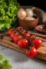 Cherry tomatoes on a blackboard, gray background with other vegetables. Farm products.