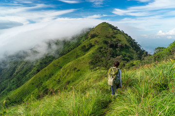 Fototapeta premium A woman trekker with backpack walking on ridge of Doi Luang Payao, summer in Thailand