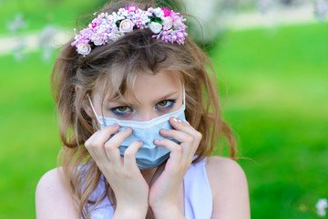 Teenager girl in medical mask in spring flowering garden. Concept of social distance and prevention of coronavirus.