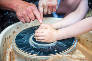 The potter makes pottery dishes on potter's wheel.