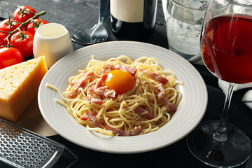 Composition with plate of tasty pasta and ingredients for cooking on wooden background