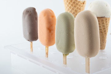 set of organic handmade ice cream of different flavors on sticks and waffle cones with vanilla,...