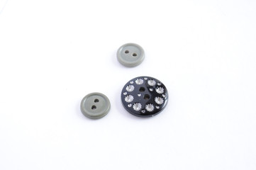 three plastic buttons of different sizes gray and black on a white background sewing accessories for clothing