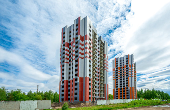 High-rise Buildings Are Rushing Into The Sky And Clouds Are Flying In Their Direction. The Houses Are Almost Finished And Colored. Residents Will Be Moving In Soon. Cozy New Apartments