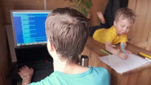 man developer work at home and helps to son, small child near play and paint, parenthood multitasking, concept of self-isolated father lifestyle, stay home in quarantine isolation, behind view