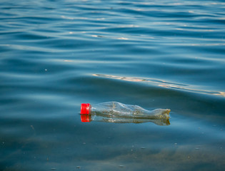 A PET plastic bottle floating on water of a lake in Bucharest, Romania. Plastic pollution environment concept.