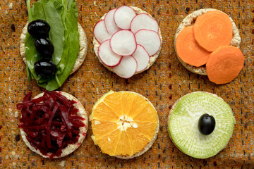 Obraz na płótnie Canvas vegetarian sandwiches. on grain loaves lie. repeating the shape of the circle radishes, green radishes, carrots, beets cut into strips, olives, sorrel and orange. it harmonizes with a warm textured da