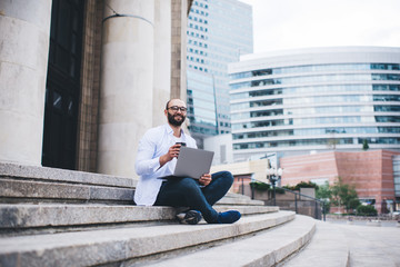 Freelance journalist with laptop sitting on stairs and waiting