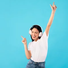 Poster Portrait of excited girl wearing headphones enjoying music © Prostock-studio