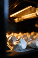 Closeup white sweet bizet or meringues in the oven with the place for your text