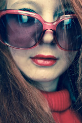 Portrait of a stylish sexy girl with red hair, red lipstick, in red glasses