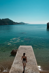 Woman on stone pier watches the Croatian coast and the Adriatic sea