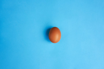 Brown egg on blue background. Real farm egg. Natural healthy food and organic farming concept