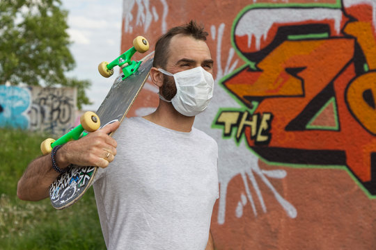 man with a skateboard and wearing an anti corona mask