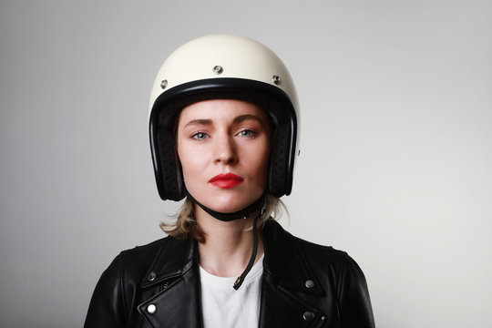 Head shot of happy biker young woman, wearing retro helmet, with red lips posing over white wall. Space for your text.