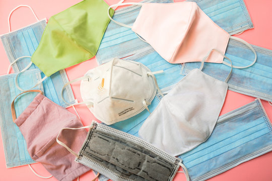 Top view of different and several type of mask such as N95 , cloth , hygiene face masks on pink background , health protection from coronavirus or COVID-19 or PM 2.5 concept