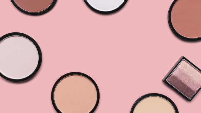 Beige blush, brown eye shadows and mineral compact face powder on a pastel pink background. Top view. Trendy colors. Makeup. Cosmetic products. Tonal foundation. Flat lay. Beauty pattern. Stop motion