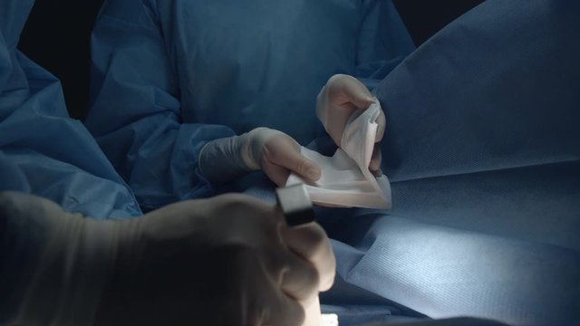 A nurse gives a surgeon a cardiac stimulator for installation