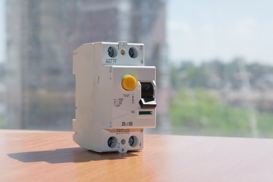 Residual current device on the table against the background of a residential building. A device for protecting human life and health from touching exposed electrical wires.