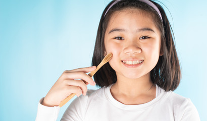An Asian child is holding a toothbrush.