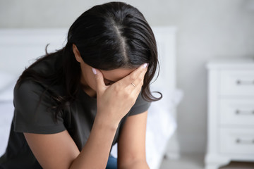 Close up view African mixed-race woman with drooping head sitting indoors feels despair due...