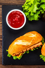 Hot dogs, French fries and vegetables on black stone board
