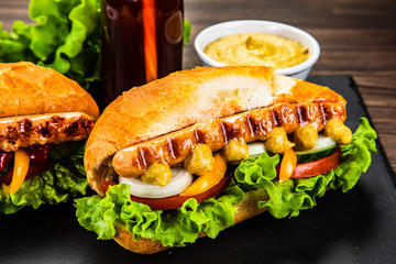 Hot dogs, French fries and vegetables on black stone board
