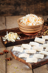 raw dumplings with sauerkraut on the board. Wooden background, varenik