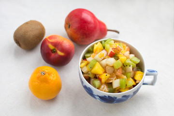 fruit salad serving in a Cup decanter milkman with fresh milk yogurt isolate on a white background kiwi nectarine pear Mandarin