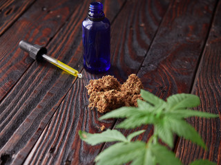 Buds, plant and marijuana oil on a rustic table. Medicinal marijuana. CBD oil. Weed.