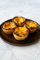 Pasteis de Nata or Belem Tart. Portuguese Custard made with Egg, Cinnamon, Sugar and Flour on Wooden Plate.