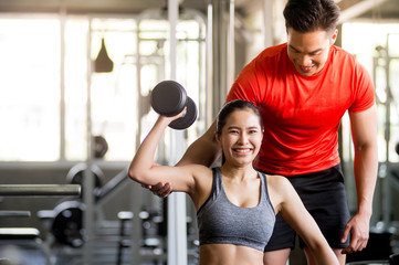 Obraz premium The trainer is teaching exercise to charming women Dumbbell Lifting Course for Strengthens Muscles, Online Live Streaming, Exercise Tutorials, Exercise Concept at Home.