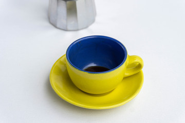Colorful dirty cup of coffee with a coffee maker on the background. Colombia colors
