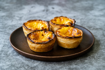 Pasteis de Nata or Belem Tart. Portuguese Custard made with Egg, Cinnamon, Sugar and Flour on Wooden Plate.