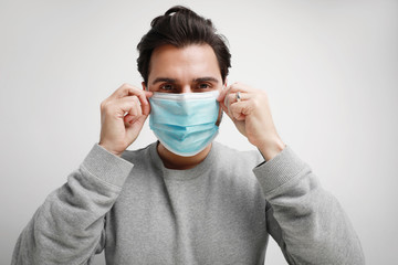 Portrait of young caucasian man in a blue medical virus mask on his face. Theme of coronavirus and safety. Horizontal.