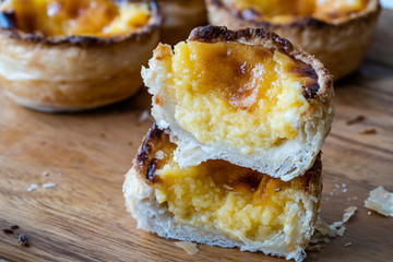 Pasteis de Nata or Belem Tart. Portuguese Custard made with Egg, Cinnamon, Sugar and Flour on Wooden Plate.