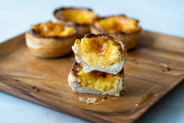 Pasteis de Nata or Belem Tart. Portuguese Custard made with Egg, Cinnamon, Sugar and Flour on Wooden Plate.