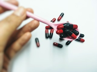 Cropped Hand Holding Capsules In Spoon Over White Background