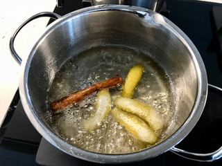 Making Sherbet with Cinnamon Stick, Lemon Peel and Water in Pot for Pasteis de Nata or Belem Tart. Portuguese Custard made with Egg, Cinnamon, Sugar and Flour.