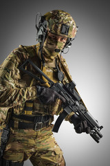 Soldier holding assault rifle. Uniform conforms to special services of the Russian Federation. Shot in studio. Isolated with clipping path on grey background