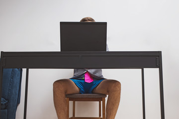 Man wearing suit jacket and blue shorts while working with his laptop.
