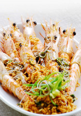 Fried shrimps on a plate topping with minced garlic