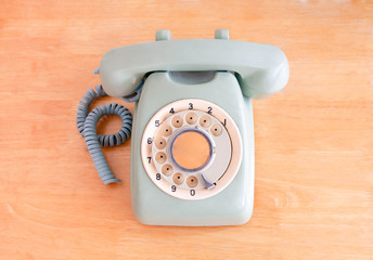 Old broken green rotary phone on wooden background. selective focus, retro and vintage style