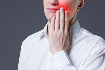 Man suffering from a toothache on gray background