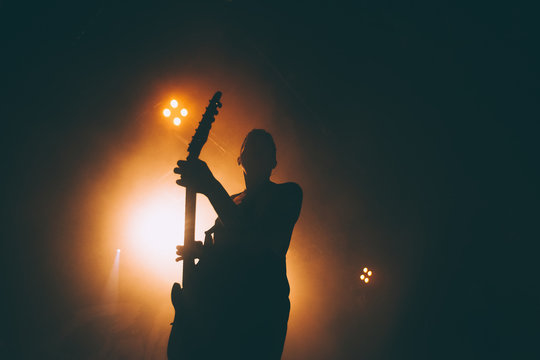 Silhouette of a guitar player in the smoke. The guitarist plays at a rock concert.