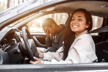 Driving instruction. A young woman learns to drive a car . Her instructor or boyfriend doesn't like the way she drives a car. But the girl is pleased with herself and does not listen to the guy.